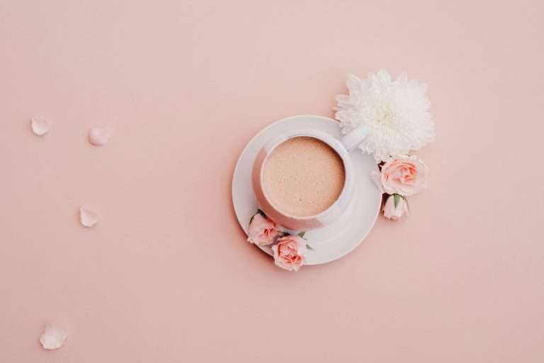 white glazed cup with saucer on pink surface
